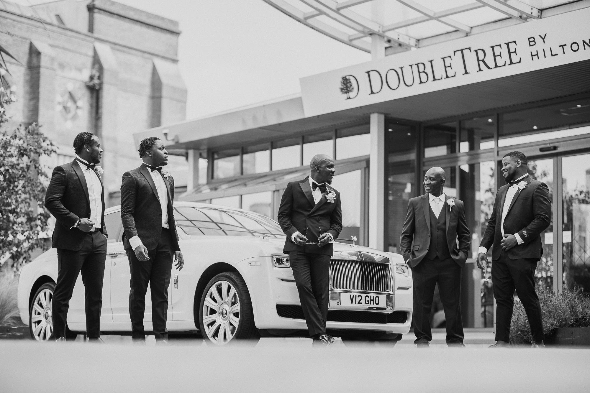 Groom with groomsmen in tuxedo's looking cool outside London wedding venue