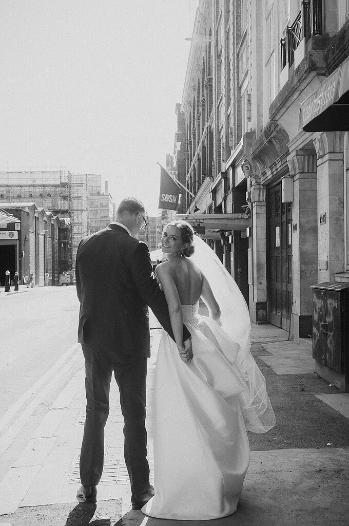 London wedding photographer; black and white wedding photography London; bride and groom walking through a London street; professional documentary wedding photography.