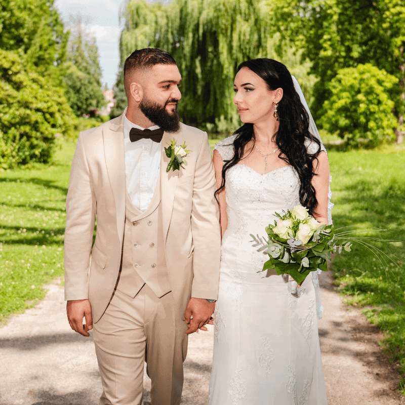Wedding couple holding hands in lush Essex park, celebrating their special day.