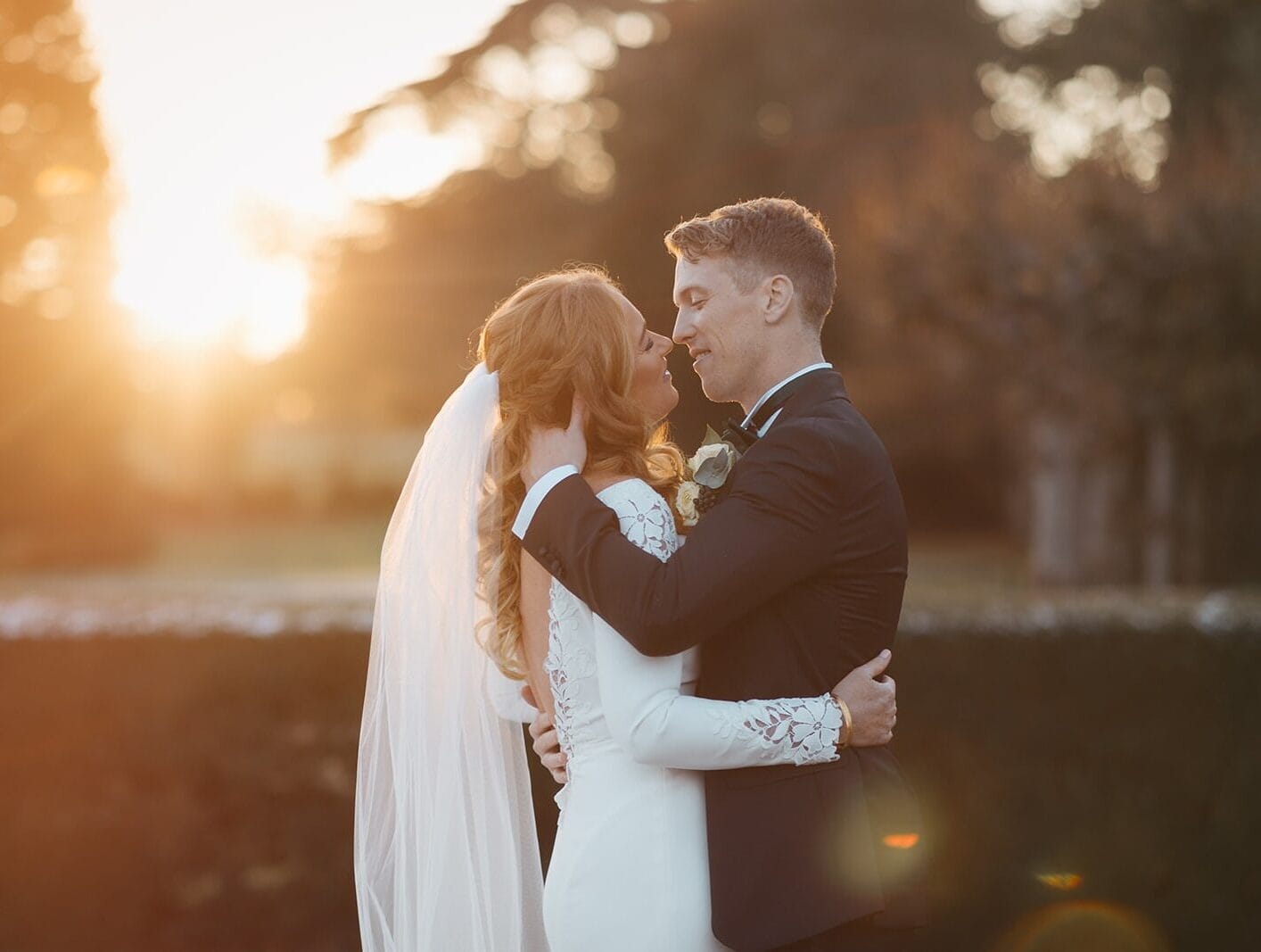 Wedding couple embracing outdoors at sunset, capturing a romantic moment.
