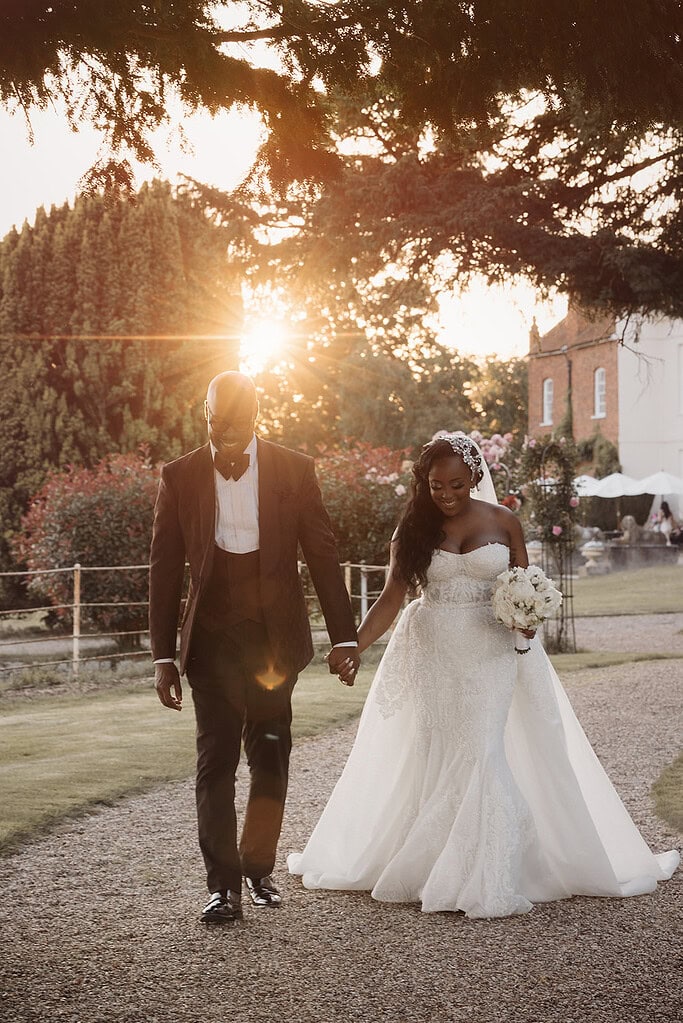 Elegant wedding couple walking hand in hand during sunset in Essex countryside.